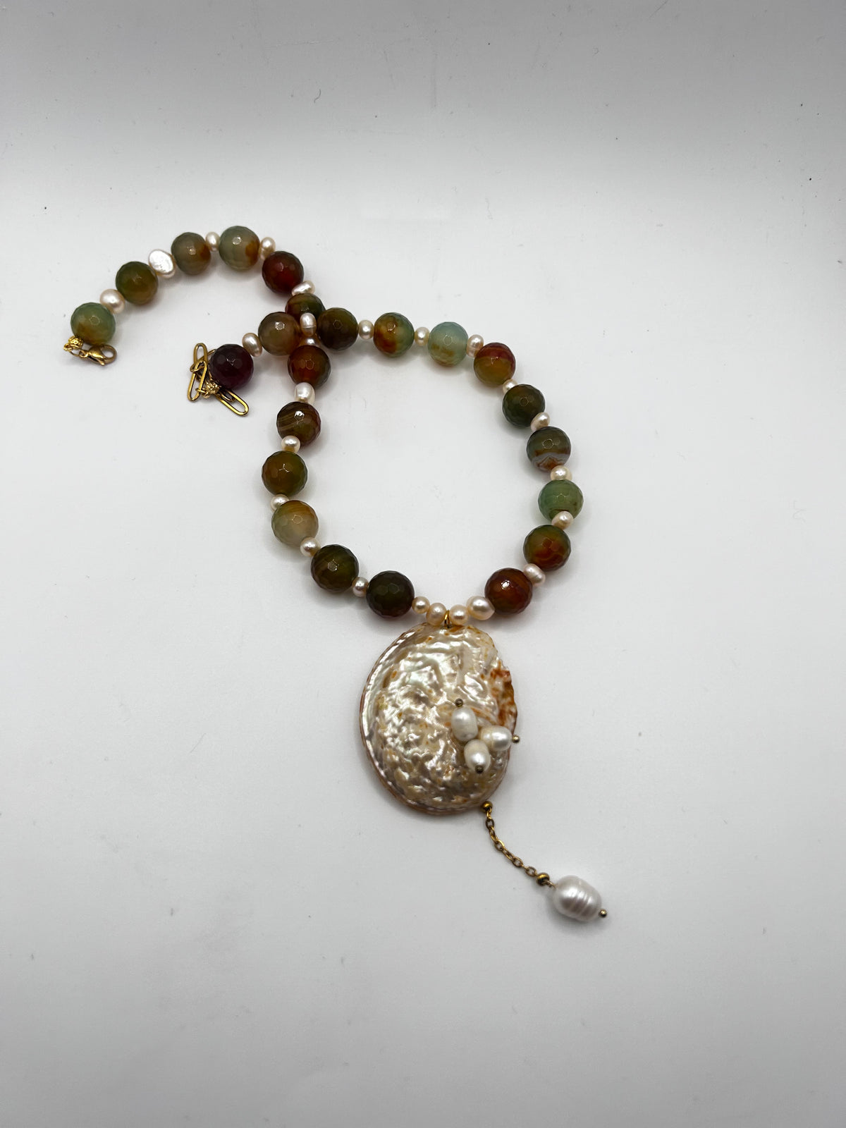 Collier artisanal en agate naturelle et perles de culture, sublimé par une abalone centrale aux reflets irisés. Un bijou marin, naturel et unique.