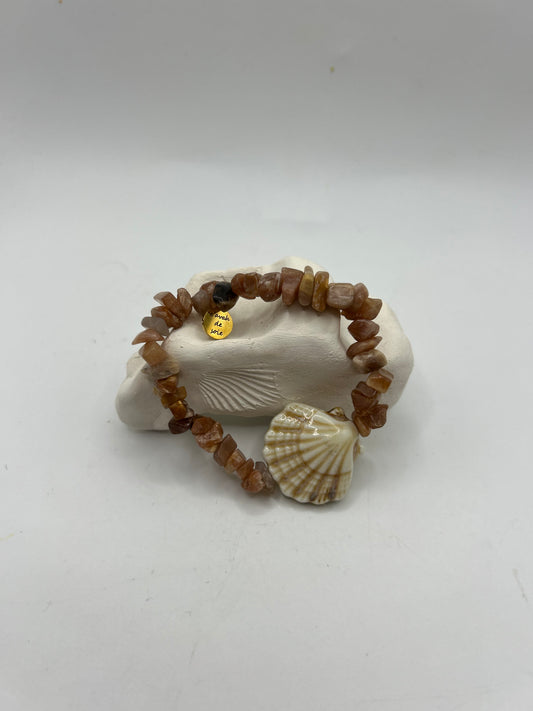 Bracelet artisanal élastique composé de pierres du soleil naturelles et d’un coquillage en céramique beige, création unique inspirée de l’océan et du style bohème méditerranéen.
