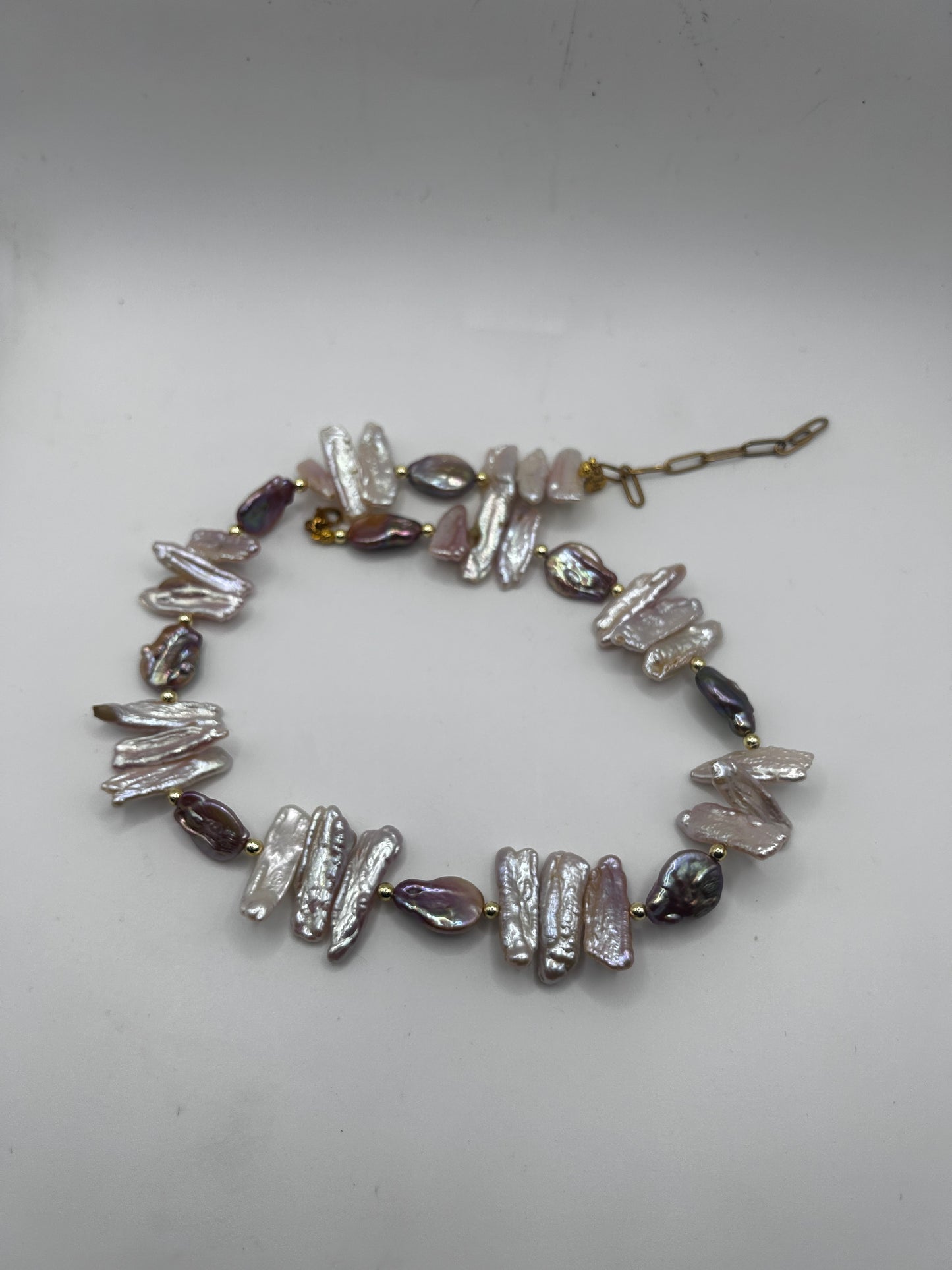 Collier en perles d’eau douce Biwa aux nuances rose, violet et nacrées, entre perles rondes et plates. Un bijou artisanal unique et délicat.