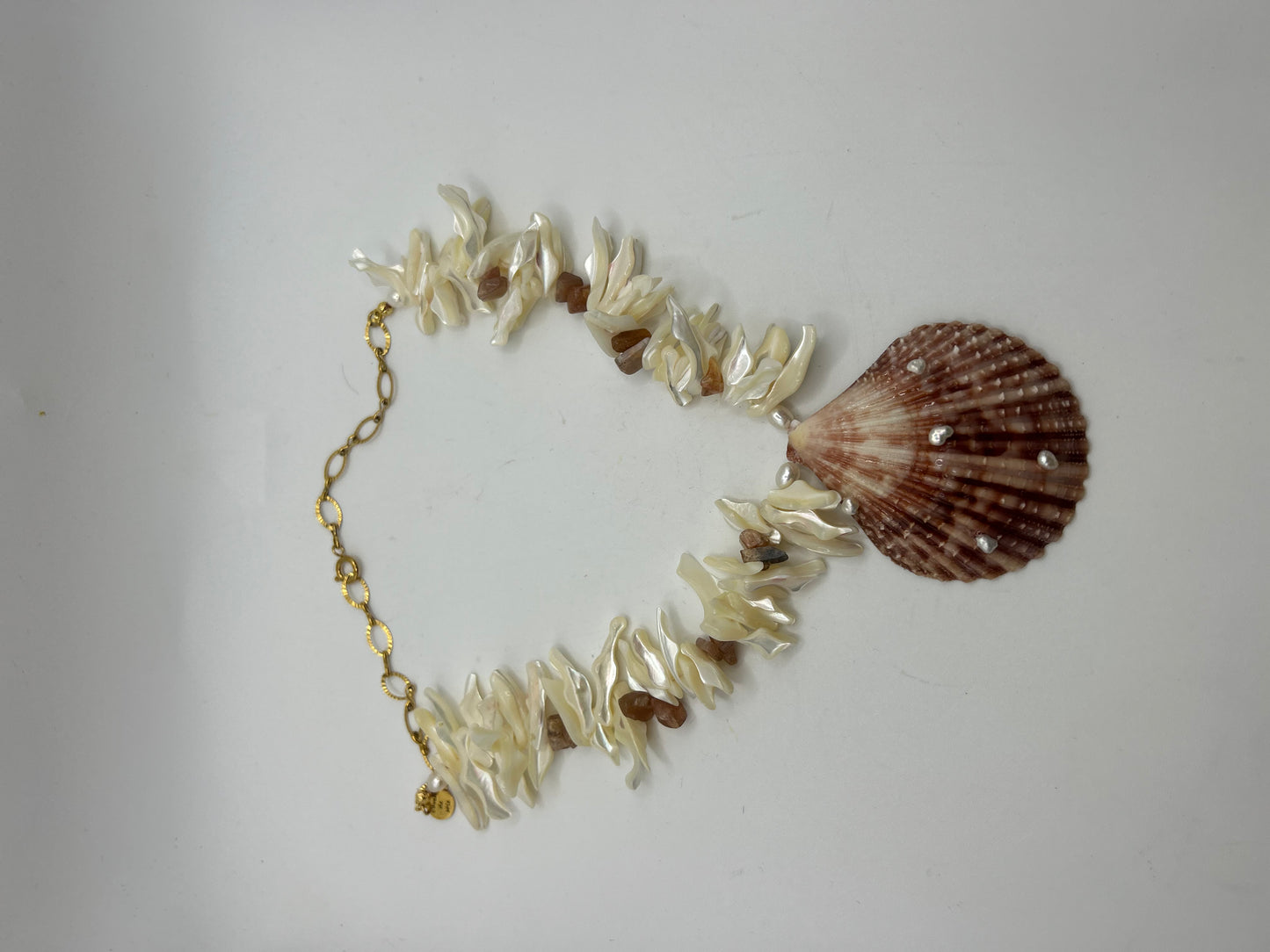 Collier artisanal en perles de coquillage, Pierre de Soleil et perles de culture avec grand coquillage central orné de perles superposées créant un effet 3D inspiré de l’océan.