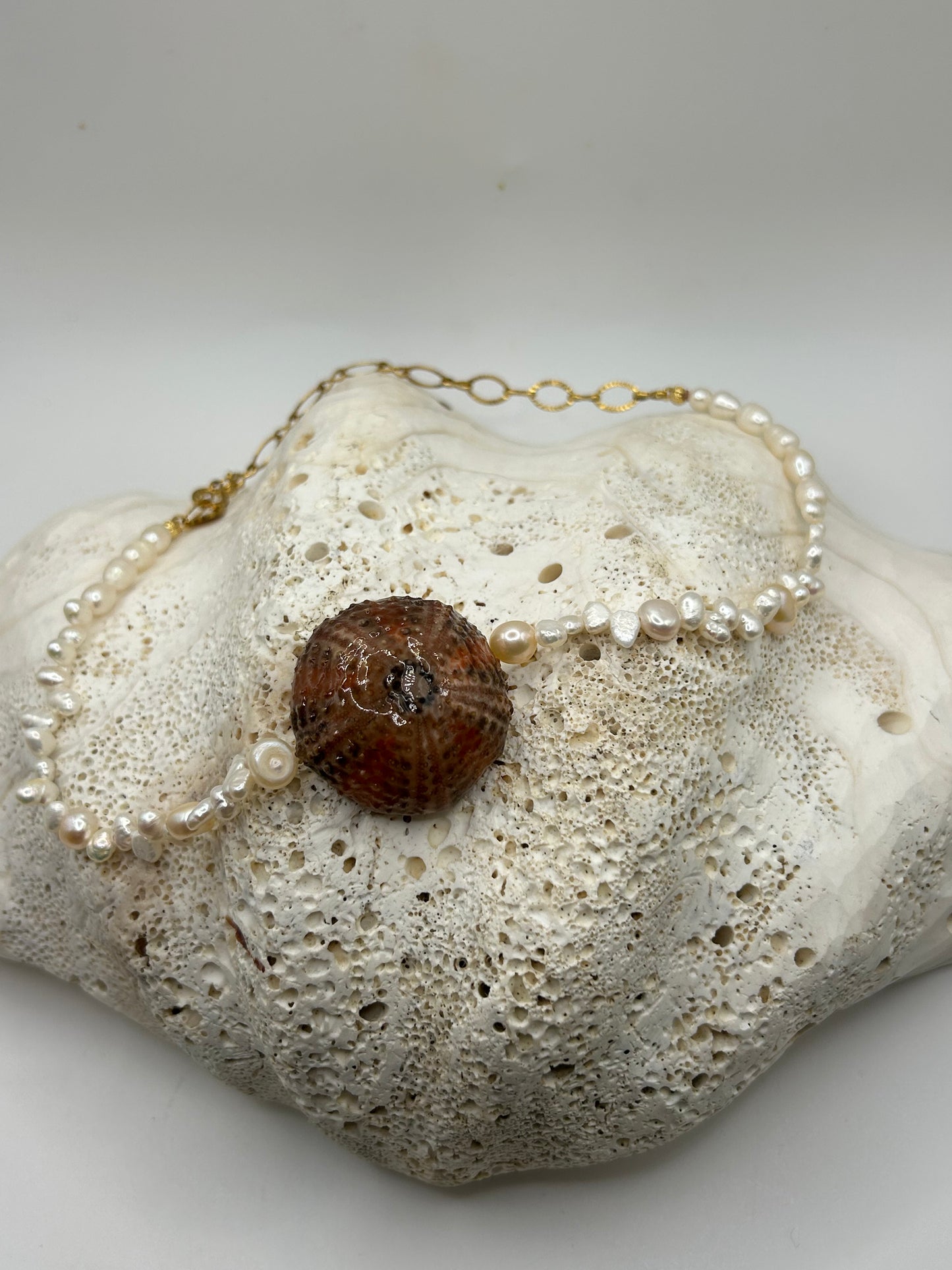 Collier artisanal avec oursin naturel orange et noir au centre et véritables perles de culture nacrées, création unique inspirée des trésors de l'océan.

